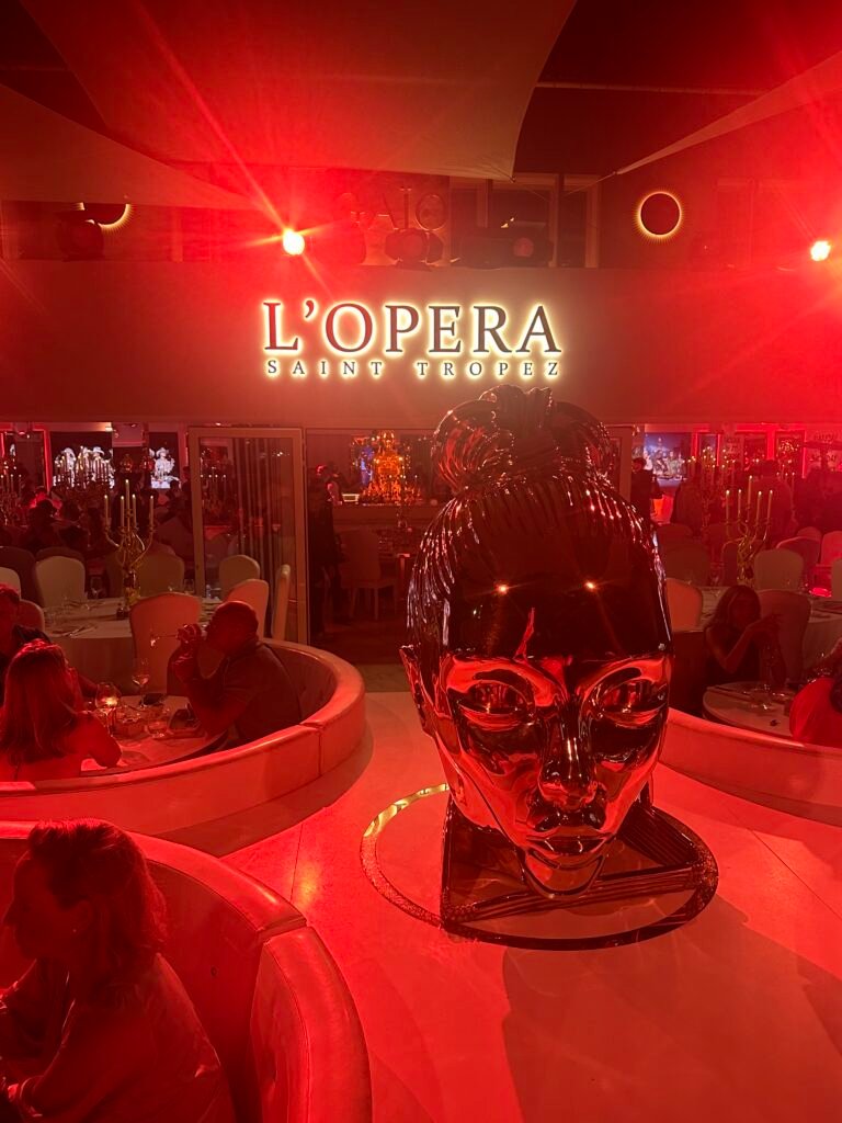 Elegant dinner setting at L’Opéra Saint-Tropez with candlelit tables, harbor views, and live performance in the background.