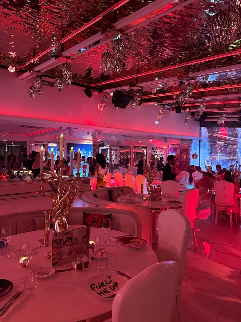 Nighttime transformation at L’Opéra Saint-Tropez featuring dancers, DJ lights, and a stylish crowd enjoying the party atmosphere.
